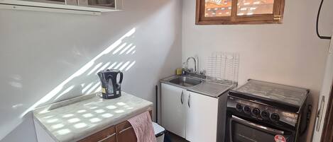 A compact kitchen with a stove, sink, and cabinets.