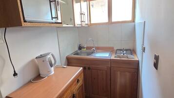 Een kleine keuken met houten kastjes, een ingebouwde magnetron, een gasfornuis en een spoelbak.