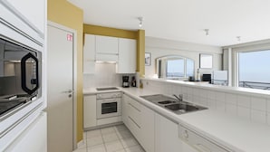 Une cuisine moderne avec des meubles blancs, un four encastré, un four à micro-ondes et un évier.