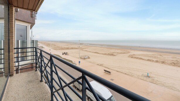 Un balcon avec vue sur une plage de sable et l’océan.