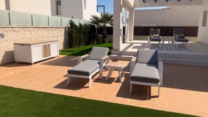 An outdoor patio with lounge chairs, a small table, and a barbecue area. - 3 Bed Villa - Sleeps 6 - Private Pool - Parking (Rojales)