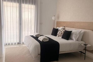A modern hotel room with a large bed, white linens, a black throw blanket, and a bedside table with a lamp. - 3 Bed Villa - Sleeps 6 - Private Pool - Parking (Rojales)