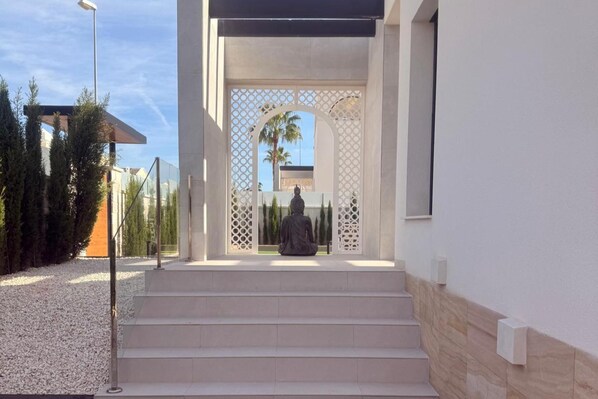 A modern entrance with a statue, steps leading up to a covered area, and a clear view of the sky. - 3 Bed Villa - Sleeps 6 - Private Pool - Parking (Rojales)