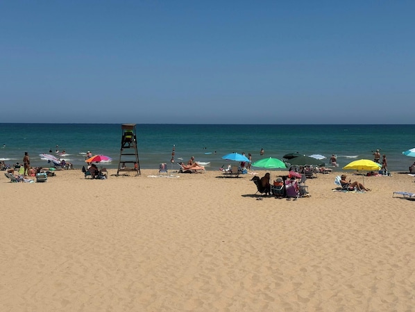 A beach with people sunbathing, umbrellas, and a lifeguard tower. - 3 Bed Villa - Sleeps 6 - Private Pool - Parking (Rojales)