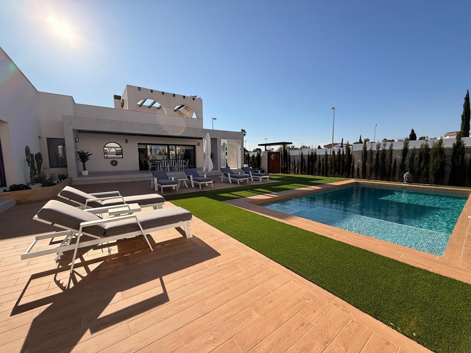A modern outdoor pool area with lounge chairs and a building with a unique architectural design.
