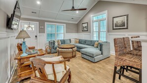 A spacious living room with a large sectional sofa, a round coffee table, and a dining area with a wooden table and chairs. - Walk to Beach & Parks! Coastal Haven in Oak Island (Oak Island)