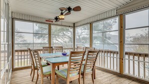 A covered patio with a wooden table and chairs, large windows, and a ceiling fan. - Walk to Beach & Parks! Coastal Haven in Oak Island (Oak Island)
