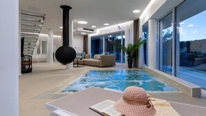 A modern indoor pool area with a lounge chair, a book, and a hat. - Villa La Bella Vista (Jelsa)