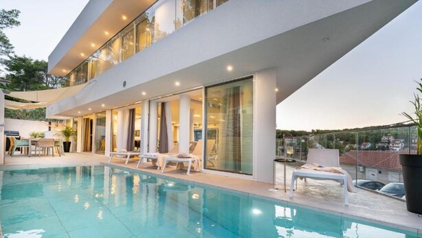 A modern poolside area with a clear pool, sun loungers, and a glass-enclosed terrace. - Villa La Bella Vista (Jelsa)