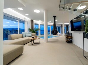 A modern interior with a pool, a sofa, a coffee table, and a TV.