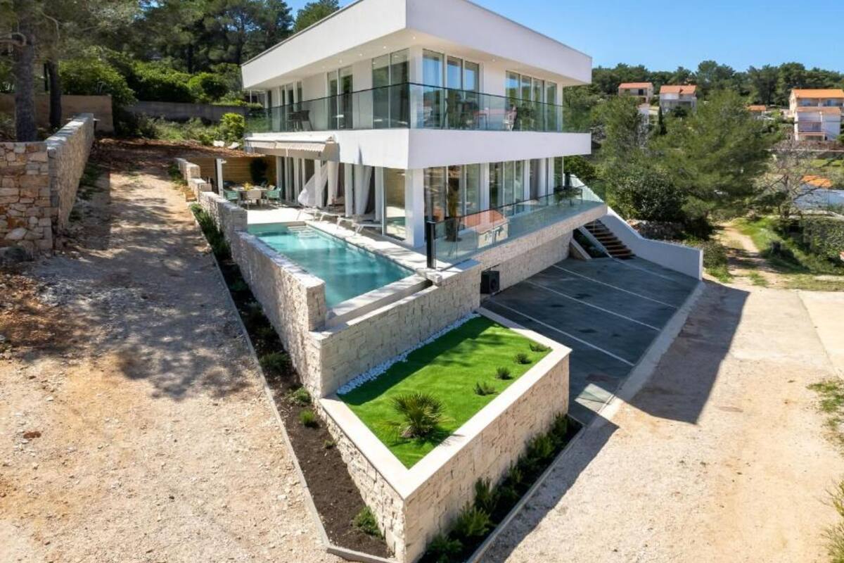 A modern two-story house with a swimming pool, a covered patio, and a landscaped garden.