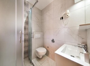 A modern bathroom with a glass shower enclosure, a toilet, and a sink with a mirror. - Privlaka Sunset Apartments (Privlaka)