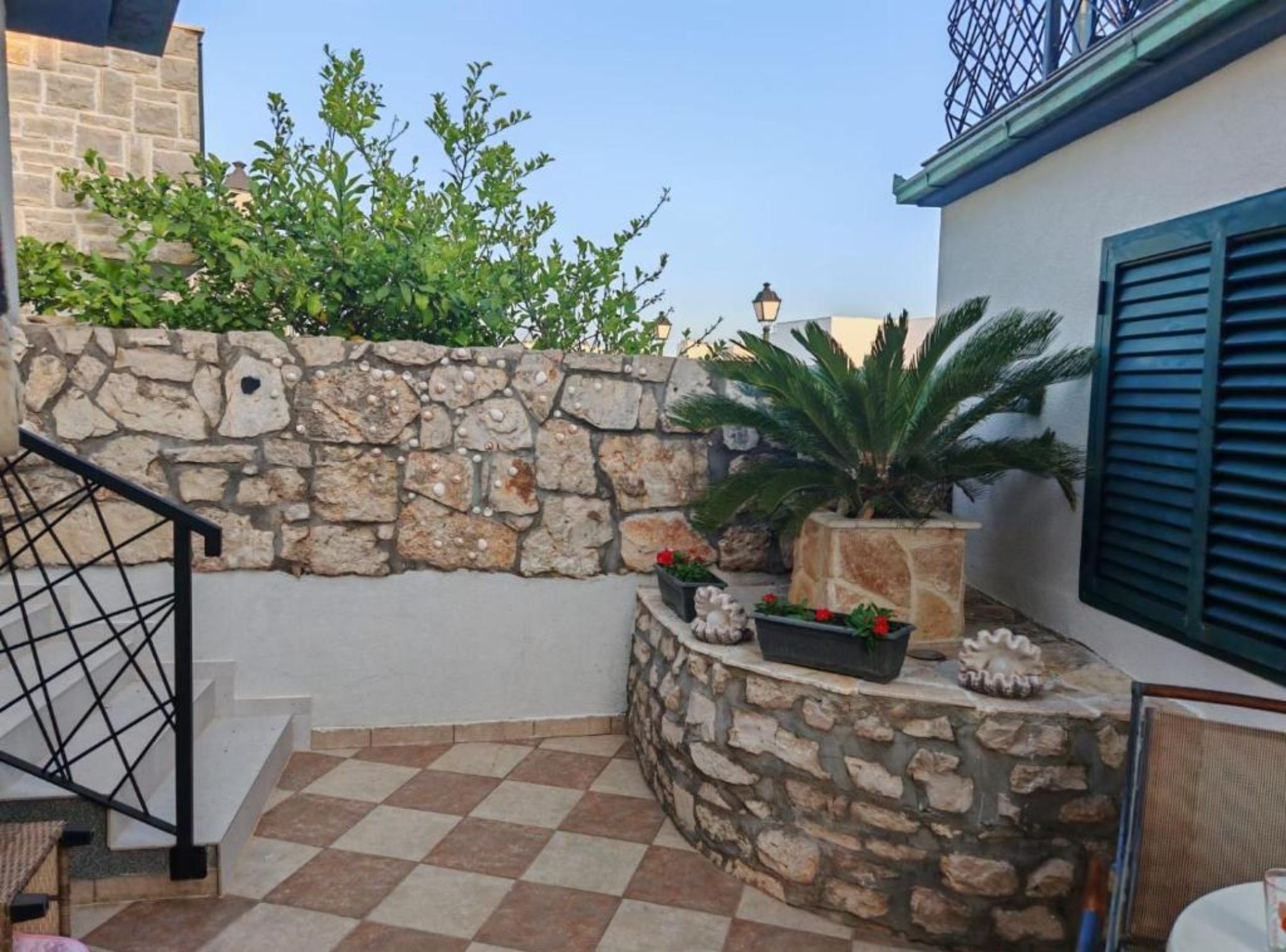 A stone wall with plants, a staircase, and a checkered floor.