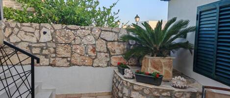 A stone wall with plants, a staircase, and a checkered floor.