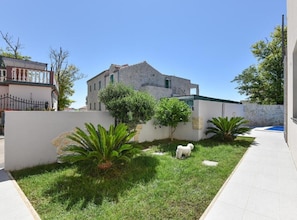 A courtyard with a small pool, surrounded by a low stone wall and lush greenery. - Privlaka Sunset Apartments (Privlaka)