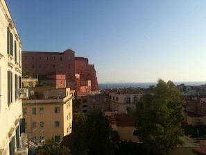 Vista de un paisaje urbano con edificios, incluyendo una estructura roja destacada y un edificio color crema con balcón.