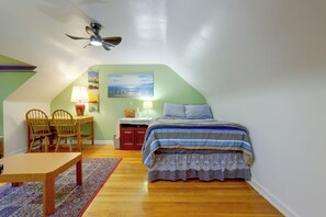 A bedroom with a bed, a desk, a chair, a lamp, and a ceiling fan.