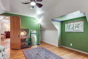 A room with a wooden door, a mirror, a lamp, a rug, and a window with blinds.