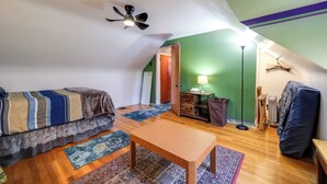 A small, cozy attic bedroom with a bed, a wooden table, a floor lamp, and a ceiling fan. - 3 Mi to UD & Kettering Health! Suburban Stay (Dayton)
