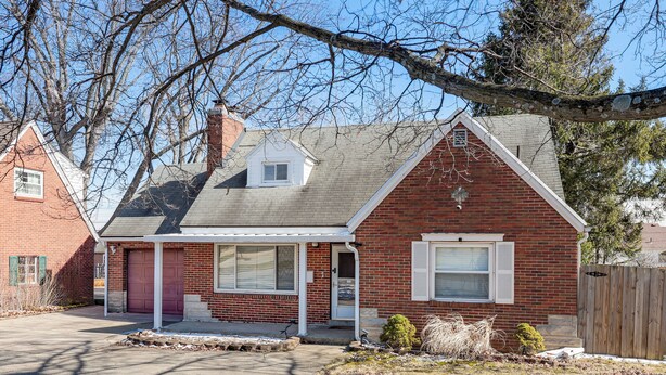 A two-story brick house with a red door, a covered porch, and a small attached garage. - 3 Mi to UD & Kettering Health! Suburban Stay (Dayton)