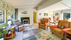 A cozy living room with a fireplace, comfortable seating, and a view of the outdoors. - Cozy Waterfront Home w/ Mtn View Near Leavenworth (Peshastin)