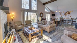 Amplia sala de estar con ventanas grandes, chimenea y una barra para café.