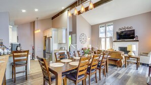 Un comedor amplio con una gran mesa de madera, varias sillas e iluminación colgante.