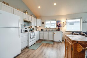 Una cocina compacta con armarios blancos, un refrigerador, una estufa y un mueble de madera.
