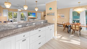 A spacious kitchen with a granite countertop, white cabinetry, and pendant lighting. - Coming soon brand new condos on the West end of Sanibel! Deeded beach access! (Sanibel)