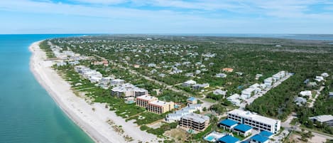 An aerial view of a coastal residential area with beachfront properties and a dense cluster of houses inland.