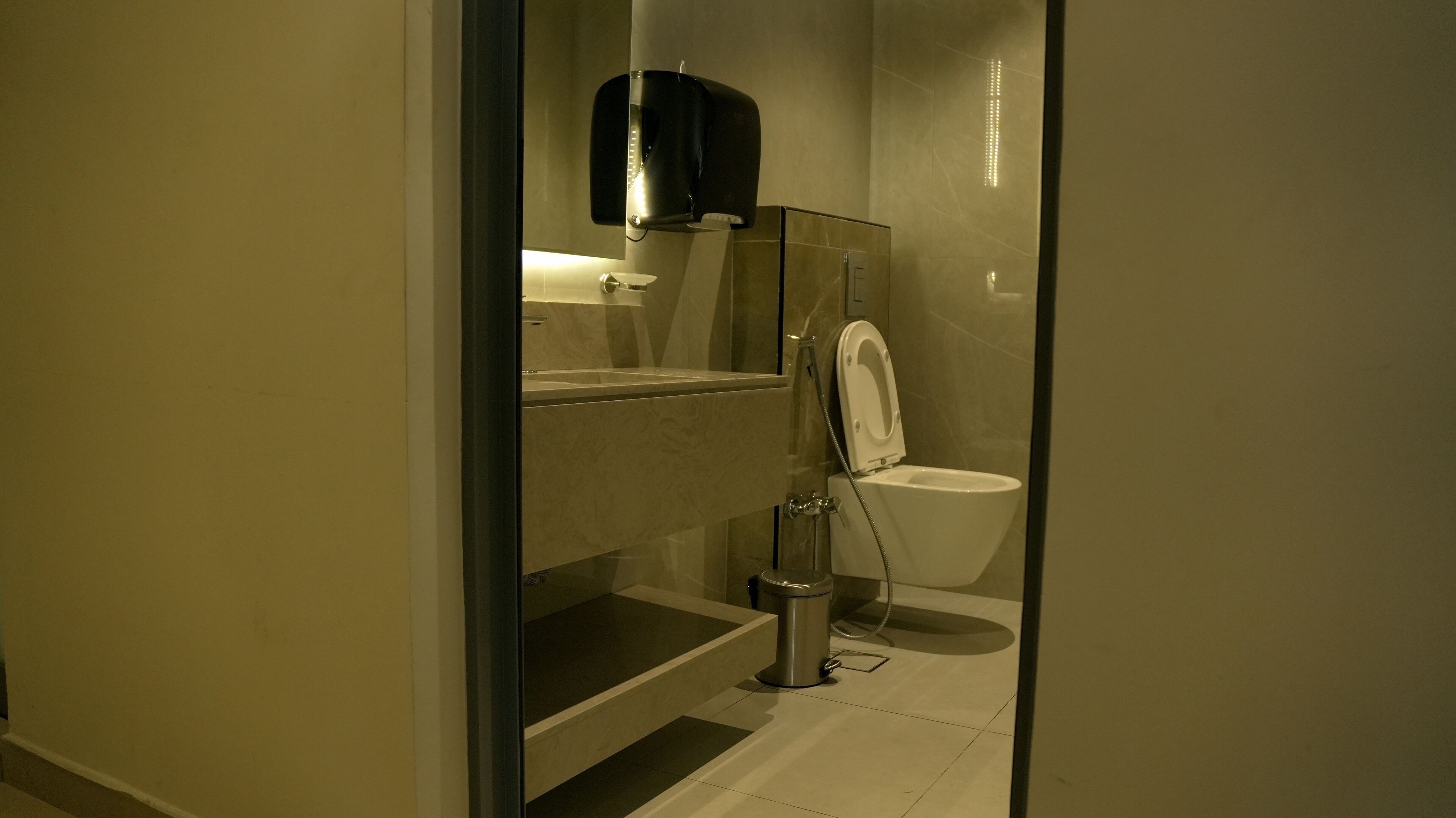 Un baño moderno con ducha de vidrio, inodoro y cubo de basura.