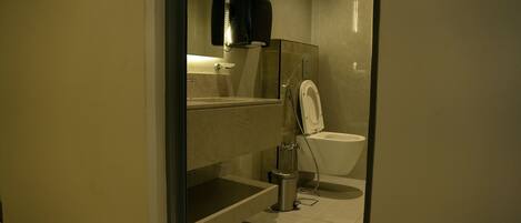 Un baño moderno con ducha de vidrio, inodoro y cubo de basura.