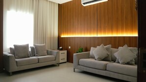 Una sala moderna con dos sofás, una mesita auxiliar y una pared de madera decorativa.