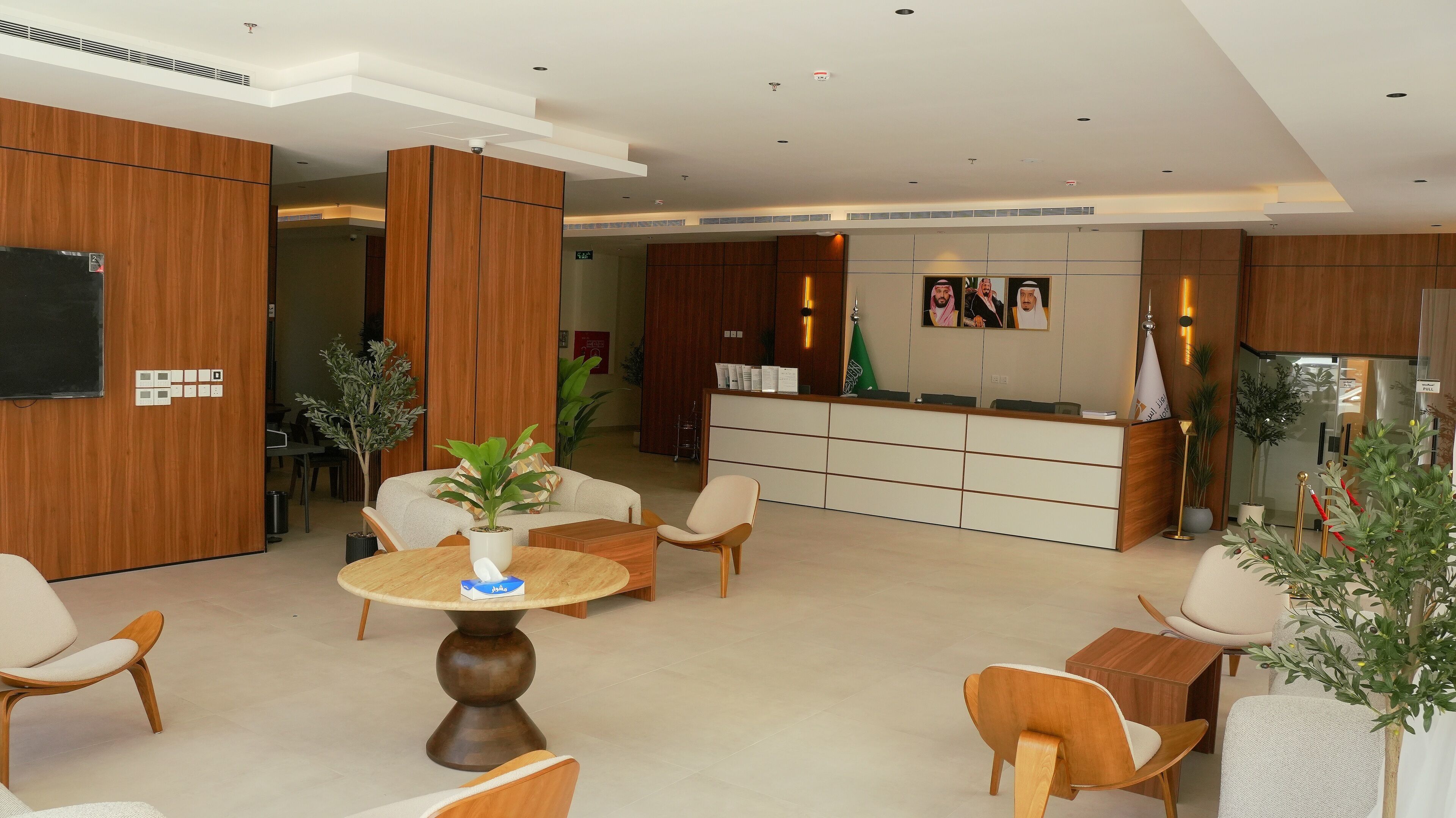 A modern hotel lobby with wooden paneling, a reception desk, seating area, and a dining space.