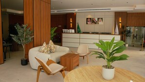 Un vestíbulo moderno de hotel con mostrador de recepción, zona de estar y plantas en macetas.