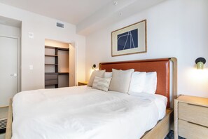 A neatly made bed with a wooden headboard, a bedside table with a lamp, and a built-in wardrobe. - NEW Penthouse with pool, hot tub, co-working, gym, lounge, games room, BBQ (Miami)