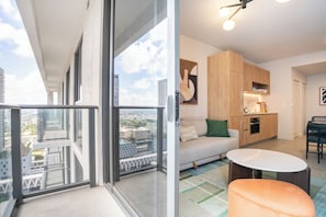 A modern apartment with a balcony, a living area with a sofa and table, and a kitchen area. - NEW Penthouse with pool, hot tub, co-working, gym, lounge, games room, BBQ (Miami)