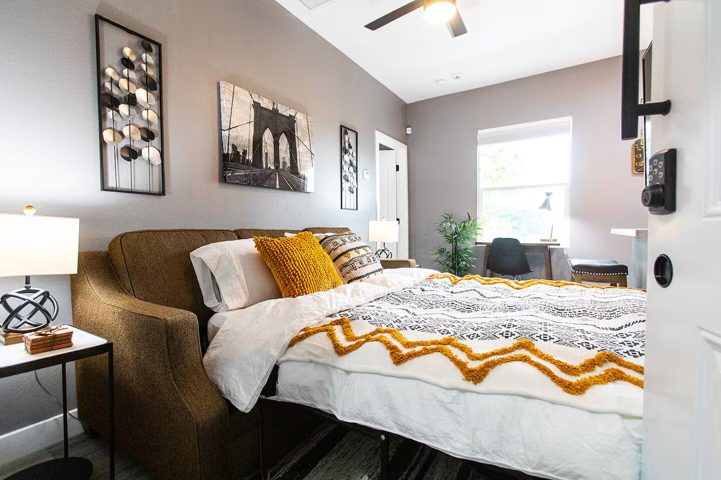 A bedroom with a large bed, a chair, a desk, and a window.
