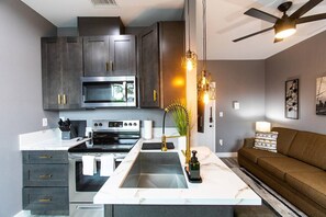 Une cuisine moderne avec des meubles de couleur sombre, une cuisinière en acier inoxydable et un plan de travail en marbre.