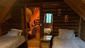 Une chambre confortable dans un chalet en bois, avec deux lits, une petite table et une chaise.