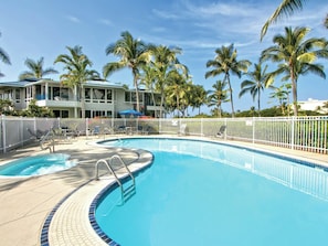 A swimming pool with a white fence, lounge chairs, and palm trees. - Club Wyndham Mauna Loa Village- 1 bedroom Condo (Kailua-Kona)
