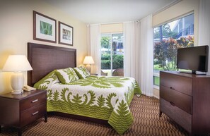 A hotel room with a bed, a TV, a desk, and a window with a view of greenery. - Club Wyndham Mauna Loa Village- 1 bedroom Condo (Kailua-Kona)