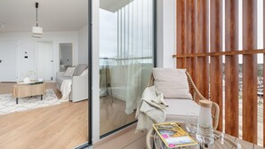 A modern living room with a glass door leading to a balcony, a sofa, a coffee table, and a magazine. - Apartment With Direct sea View (Rewal)