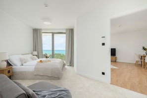A modern bedroom with a bed, bedside table, and a view of the sea. - Apartment With Direct sea View (Rewal)