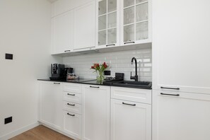 A modern kitchen with white cabinets, a black countertop, and a coffee maker. - Apartment With Direct sea View (Rewal)