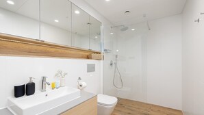 A modern bathroom with a large mirror, a wooden vanity, a white sink, and a glass-enclosed shower. - Apartment With Direct sea View (Rewal)