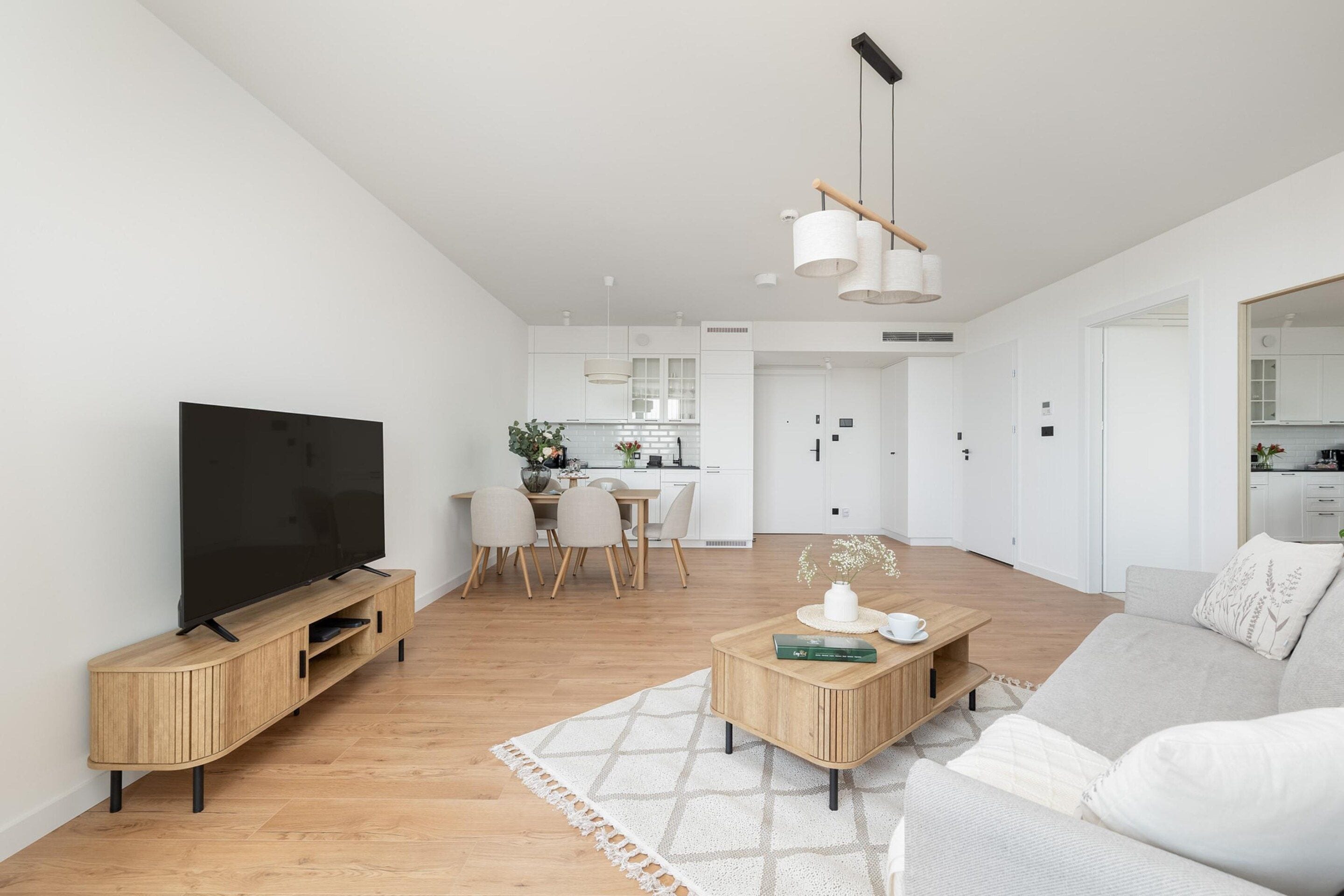 A modern living room with a flat-screen TV, wooden entertainment unit, and a sofa.