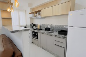 A modern kitchen with white cabinets, a marble backsplash, and a built-in oven.