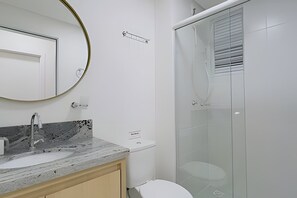 Une salle de bain moderne avec un lavabo en marbre, des toilettes et une douche à parois de verre.