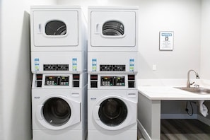 A laundry room with four stacked front-loading washing machines and a sink.